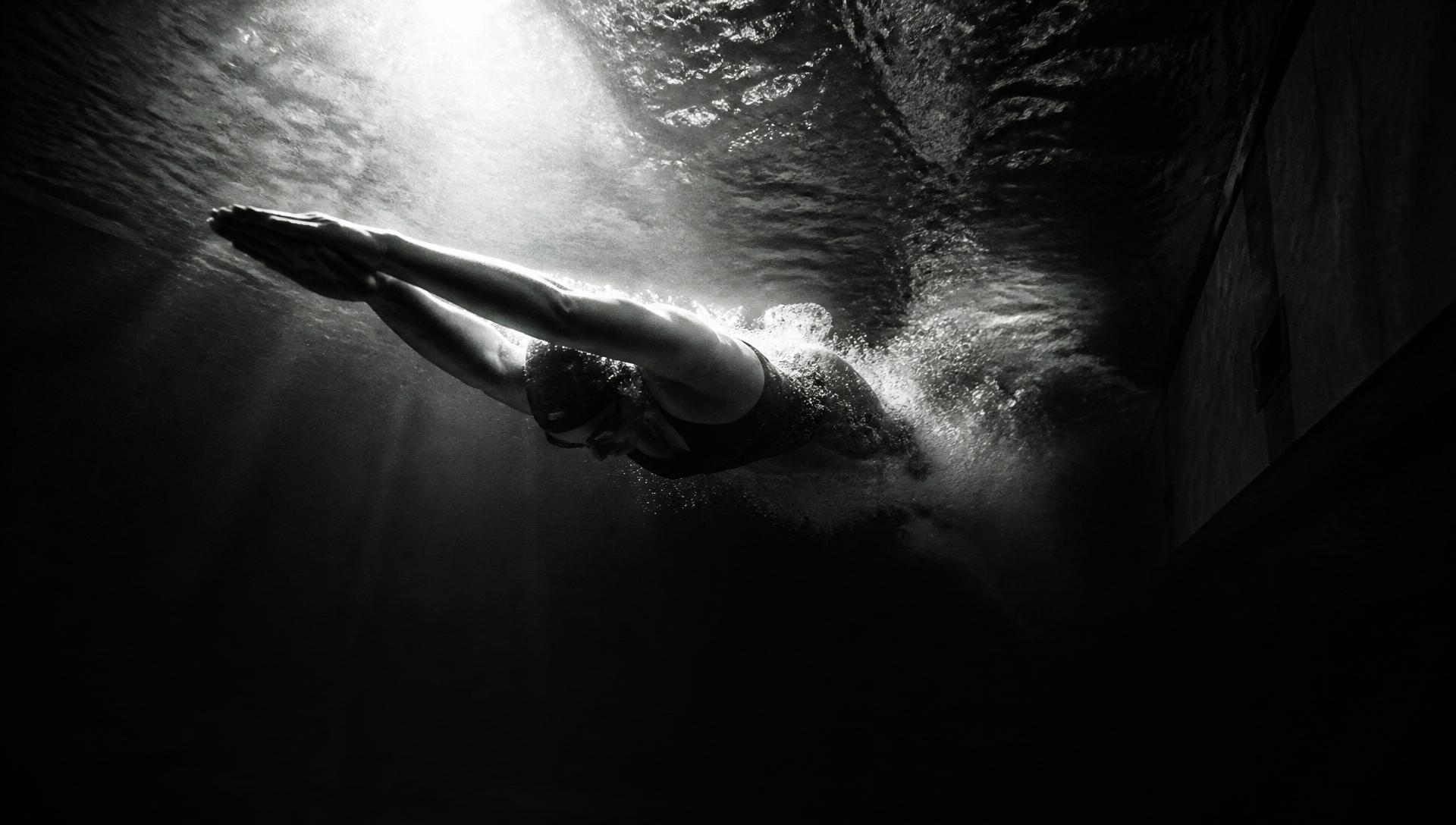 Nadador empujando del muro bajo el agua, fotografía en blanco y negro.